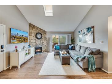 Inviting living room with stone fireplace, plush sectional, and sliding glass doors to a balcony at 3325 S Ammons St # 4-206, Lakewood, CO 80227