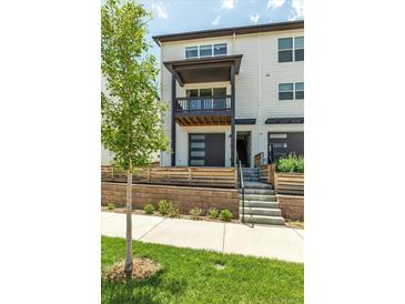 Modern two-story townhome featuring a balcony, gray garage door, and well-manicured landscaping at 2108 Alcott Way, Broomfield, CO 80023