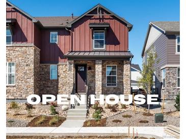 Two-story home with stone and red siding, welcoming front porch, and landscaping at 8115 Mt Harvard Rd, Littleton, CO 80125