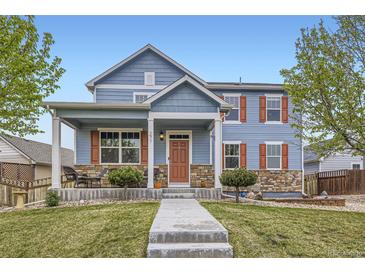 Charming two-story blue home with a welcoming front porch and meticulously maintained lawn at 277 Jewel St, Brighton, CO 80603