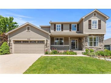 Charming two-story home with stone accents, a covered porch, an attached two-car garage and well-manicured lawn at 7099 Cerney Cir, Castle Pines, CO 80108