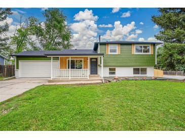 Charming home with green siding, white trim, a well-maintained lawn, and a two-car garage at 6498 S Everett Way, Littleton, CO 80123