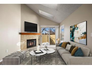 Bright living room featuring a fireplace, skylight, and sliding glass doors to a private outdoor space at 8690 Allison St # H, Arvada, CO 80005