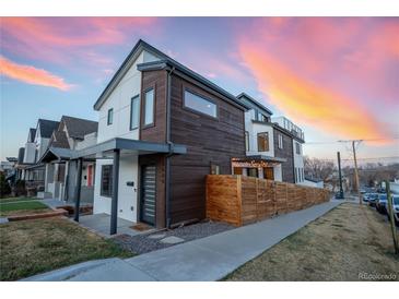 Modern home featuring wood and stucco siding, with a privacy fence and beautiful sunset in the background at 3600 N Pecos St, Denver, CO 80211
