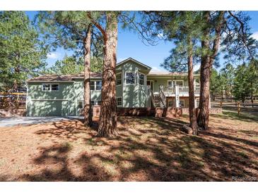 Charming green two-story home with brick foundation and a beautiful wooded front yard at 4185 Red Rock Dr, Larkspur, CO 80118