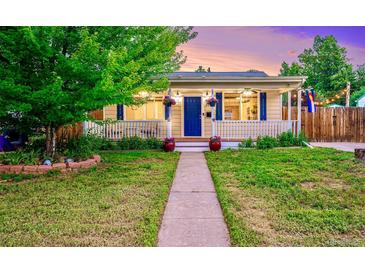 Charming home featuring a covered porch, blue door, and well-manicured lawn at 2530 S Knox Ct, Denver, CO 80219