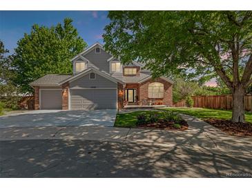 Charming two-story home featuring a brick and gray exterior, well-manicured lawn, and inviting front porch at 10345 Lions Heart, Lone Tree, CO 80124