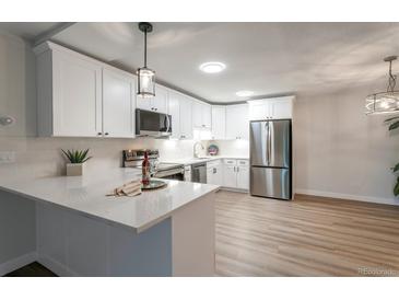 Bright kitchen features modern, stainless steel appliances and quartz countertops with a decorative pendant light at 625 S Alton Way # 3A, Denver, CO 80247