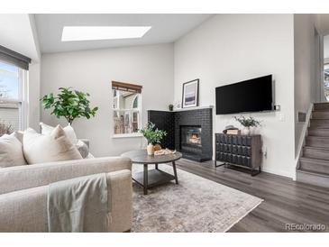 Bright living room with large windows, black brick fireplace, and comfortable furniture at 13040 W 63Rd Pl # C, Arvada, CO 80004