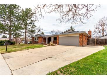 Charming red brick ranch-style home featuring an attached two car garage, a large front yard, and mature shade trees at 699 S Oswego St, Aurora, CO 80012