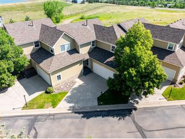 Aerial view of a tan townhome with a two-car garage, situated in a neighborhood with mature trees and green spaces at 211 Rockview Dr, Superior, CO 80027