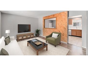 Cozy living room features a decorative wooden accent wall, modern furnishings and a window to the kitchen at 16720 E Layton Ave, Aurora, CO 80015