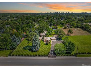 Expansive property with manicured lawn, mature trees, and a sprawling home under a beautiful sunset at 4600 S University Blvd, Englewood, CO 80113