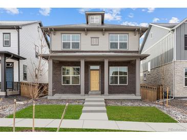 Charming two-story home featuring brick accents, a welcoming front porch, and a bright yellow front door at 21204 E 63Rd Dr, Aurora, CO 80019