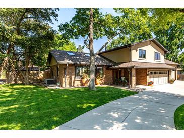 Charming brick two-story home with a well-manicured lawn and a long concrete driveway on a sunny day at 6740 S Windermere St, Littleton, CO 80120