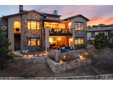 Stunning two-story home featuring stone accents, a balcony, and an outdoor living space at 8310 Raphael Ln, Littleton, CO 80125