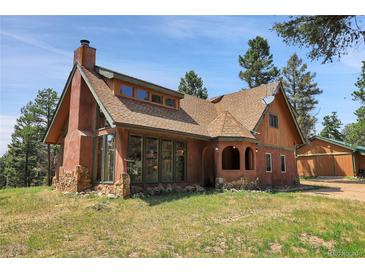 Charming stucco home with stone accents, a unique roofline, and lush surrounding trees at 26526 Gray Buck Trl, Conifer, CO 80433