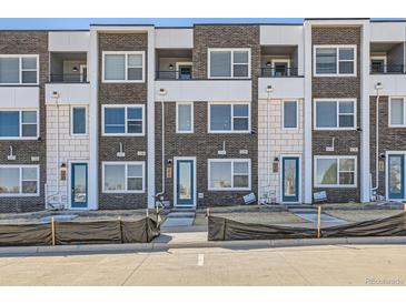 Modern townhome exterior with brick facade, private balconies, and vibrant blue entry doors at 374 N Geneva St, Aurora, CO 80010