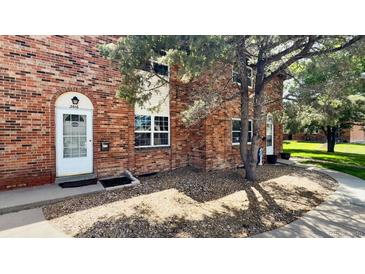 Charming brick townhouse featuring a white front door and meticulously maintained landscaping at 3616 W Radcliff Ave, Denver, CO 80236