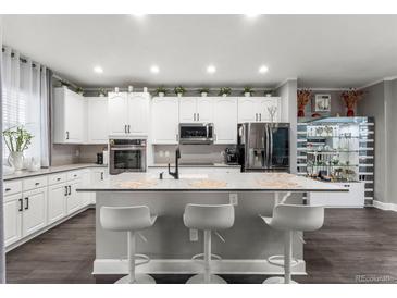 Well-lit kitchen featuring a center island with barstool seating and modern appliances at 3818 S Dallas St, Aurora, CO 80014