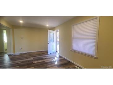 Bright living room featuring updated flooring and natural light from a window and glass door at 1940 Quince St, Denver, CO 80220
