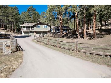 Charming home with a split rail fence, a long driveway, and a two-car garage at 24949 N Mountain Park Dr, Evergreen, CO 80439