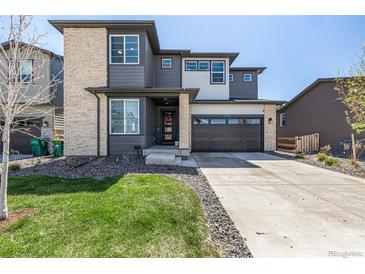 Modern two-story home with stone accents, gray siding, well maintained lawn, and a two car garage on a sunny day at 23652 E 40Th Ave, Aurora, CO 80019