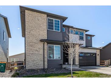 Modern two-story home with stone accents and a paved driveway and a two-car garage with a well kept lawn at 23652 E 40Th Ave, Aurora, CO 80019