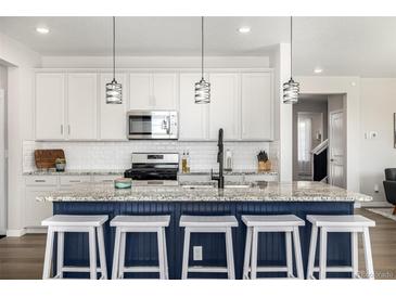 Bright kitchen features a large island, granite countertops, modern lighting, and stainless steel appliances at 23652 E 40Th Ave, Aurora, CO 80019