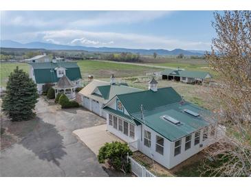 Picturesque farm with white buildings, gazebo, green metal roofs, and mountain views in the background at 6231 Prospect Rd, Longmont, CO 80503