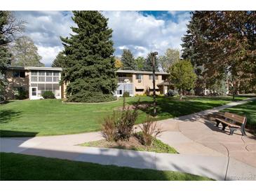 Charming apartment building with lush green lawn and mature trees providing shade at 675 S Clinton St # 8B, Denver, CO 80247