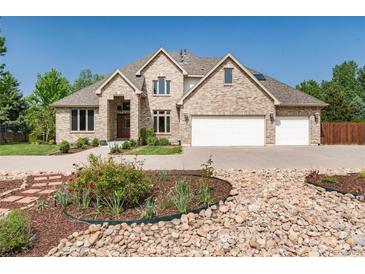 Beautiful tan brick home with a three car garage and a well manicured front yard and flower beds at 4245 S Dawson St, Aurora, CO 80014