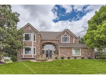 Charming two-story brick home with a well-manicured lawn and inviting front entrance at 7758 Edgewater Ct, Lone Tree, CO 80124