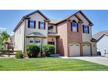 Beautiful two-story home featuring a brick facade and well-manicured lawn at 11951 Singing Winds St, Parker, CO 80138