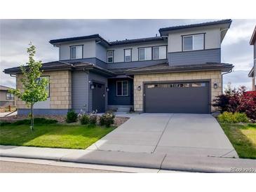 Two-story house with gray siding, stone accents, and a two-car garage at 11099 Pastel Pt, Parker, CO 80134