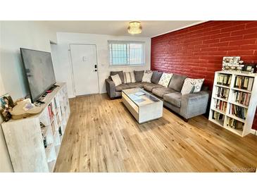 Inviting living room features a comfortable sectional sofa, red brick accent wall, and bright natural light at 6800 E Tennessee Ave # 351, Denver, CO 80224