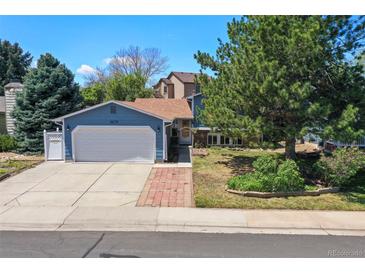 Charming blue two-story home features a well-manicured lawn, brick walkway, and an attached two-car garage at 8679 Apache Plume Dr, Parker, CO 80134
