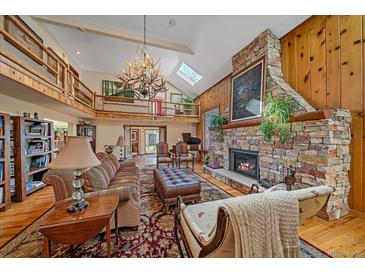 Inviting living room with stone fireplace, wood paneling, and antler chandelier, perfect for cozy evenings at 25601 Centennial Trl, Golden, CO 80401