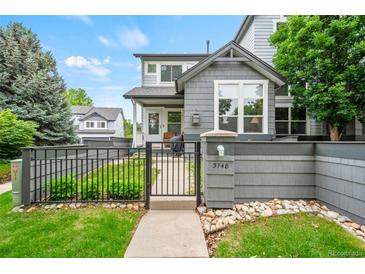 Charming home exterior with well-maintained lawn and decorative stone accents, enhanced by a stylish dark metal fence and gate at 3748 Oakwood Dr, Longmont, CO 80503