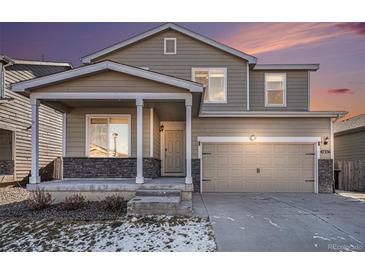 Two-story house with beige siding, stone accents, and a two-car garage at 47356 Lilac Ave, Bennett, CO 80102