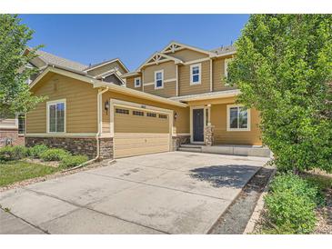 Tan two-story home featuring a two-car garage and charming stone accents at 6612 S Muscadine Ct, Aurora, CO 80016