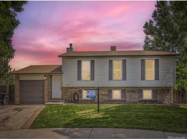 Charming two-story home with vinyl siding, brick accents, landscaped lawn, and an attached garage at 11062 Hudson Ct, Thornton, CO 80233
