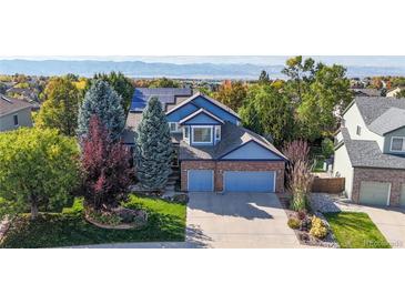 Inviting two-story home with a well-manicured lawn, mature trees, and a two-car garage at 10047 Sylvestor Rd, Highlands Ranch, CO 80129