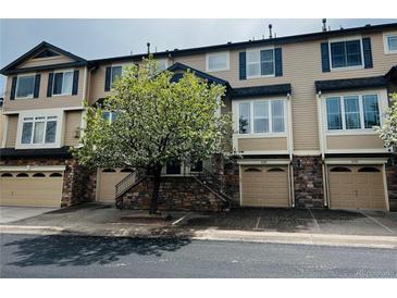 Charming exterior view of townhome with garage, stone accents, blue shutters, and a flowering tree in front at 11328 W Radcliffe Dr, Littleton, CO 80127
