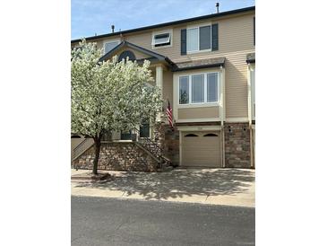 Charming townhome featuring a stone facade, attached garage and beautiful flowering tree at 11328 W Radcliffe Dr, Littleton, CO 80127