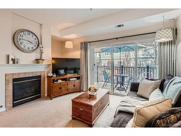 Comfortable living room featuring a fireplace, entertainment center, and sliding doors to a private balcony at 2769 W Riverwalk Cir # E, Littleton, CO 80123