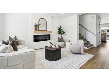 Bright living room features a modern fireplace, stylish furniture, and wood-look flooring at 6722 S Independence St, Littleton, CO 80128