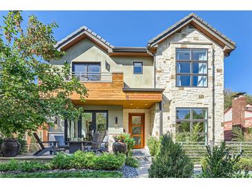 Two-story home with stone and wood accents, a balcony, and a landscaped front yard at 1237 S Saint Paul St, Denver, CO 80210