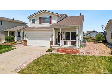 Charming two-story home features a manicured lawn, an attached two-car garage, and a covered front porch at 9579 Bighorn Way, Littleton, CO 80125
