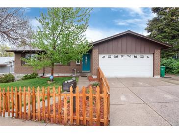 Charming brick home featuring a bright blue front door, fenced yard, and a two-car garage with an extended driveway at 3150 S Pitkin St, Aurora, CO 80013